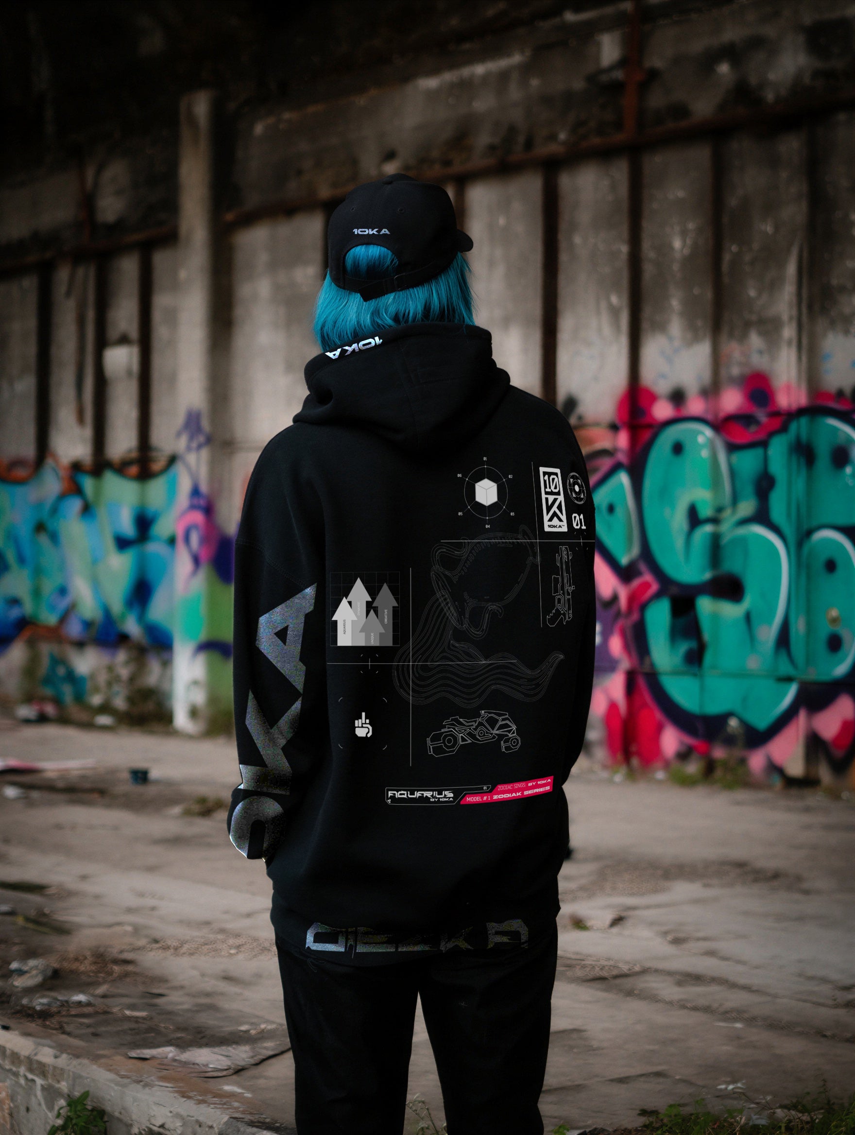 Model wearing the Zodiac Hoodie Aquarius by 10KA in an urban setting, back view, showcasing experimental futuristic graphics inspired by innovation and freedom.
